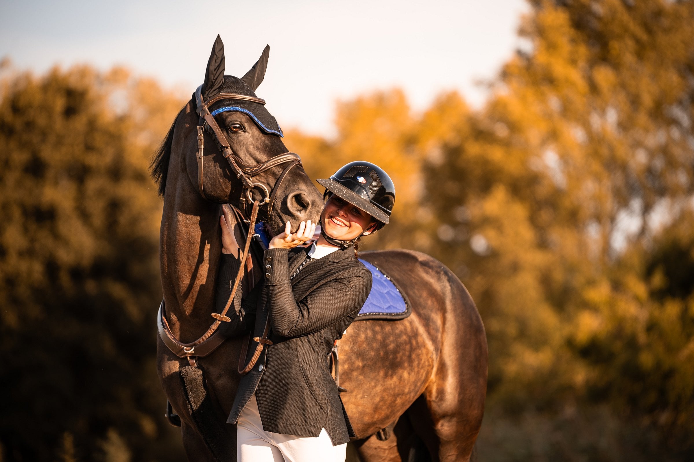 Cavalière contre la tête d'un cheval bai, tapis de selle bleu roi
